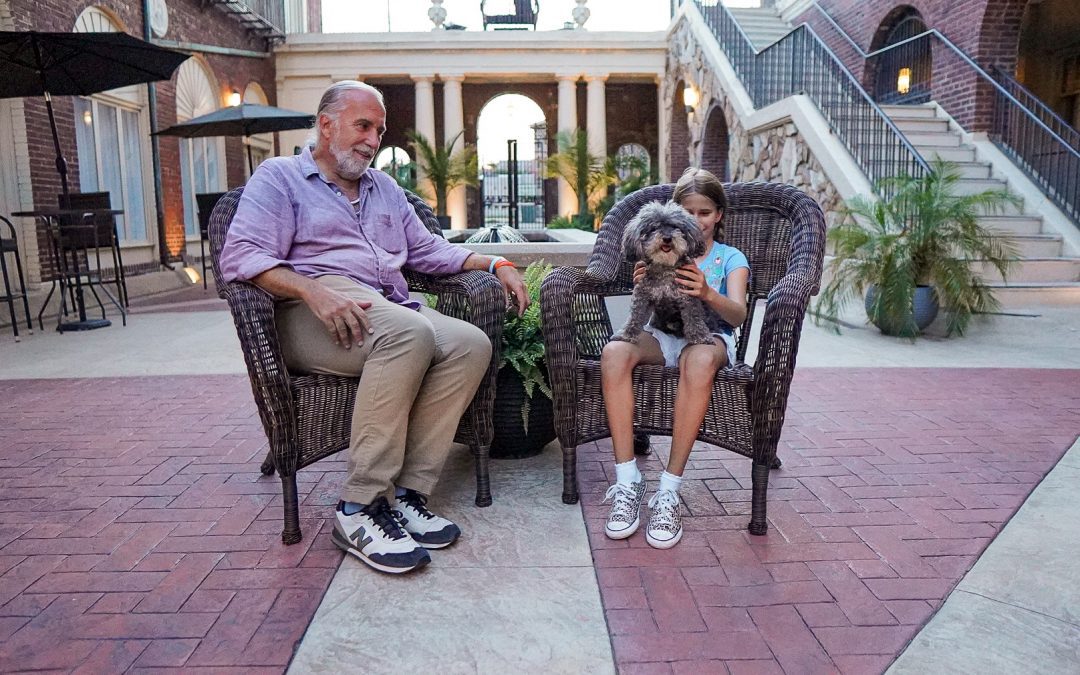 man and grandfather with their dog in the courtyard at Omaha's Magnolia Hotel
